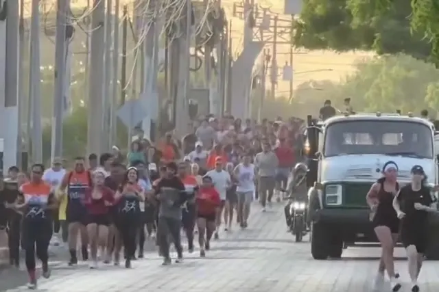Calle llena de corredores detrás de la camioneta de escolta